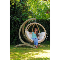 Women sitting in hanging egg chair attached to wooden frame