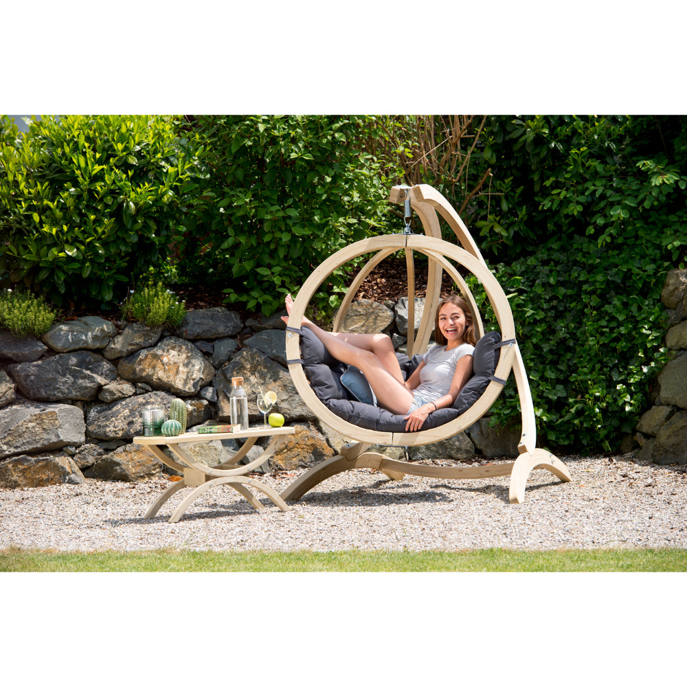 Smiliing women resting comfortably in a hanging egg basket in garden setting