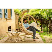 Man relaxing in garden patio while sitting in hanging nest basket