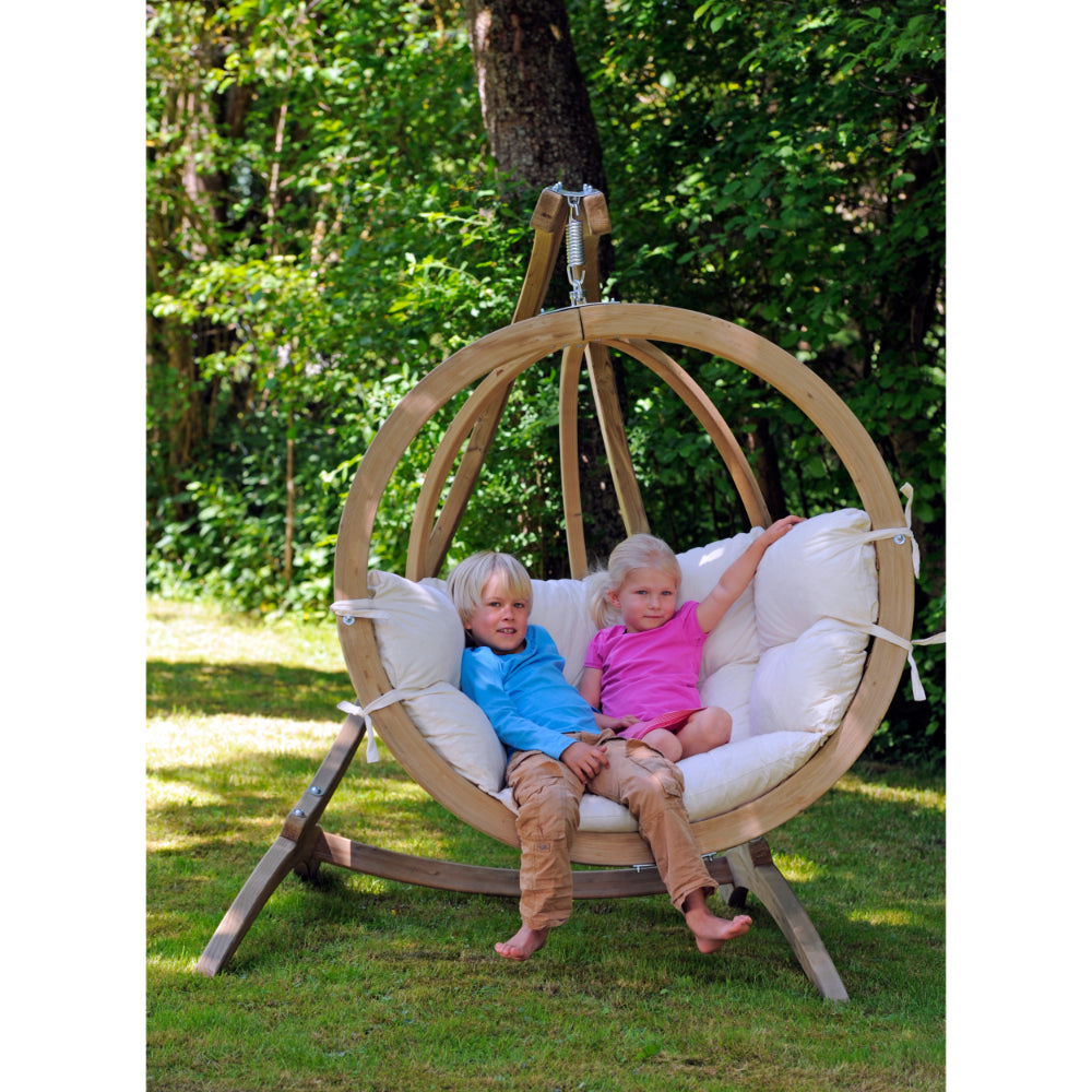 Two children playing in hanging nest egg basket in garden setting