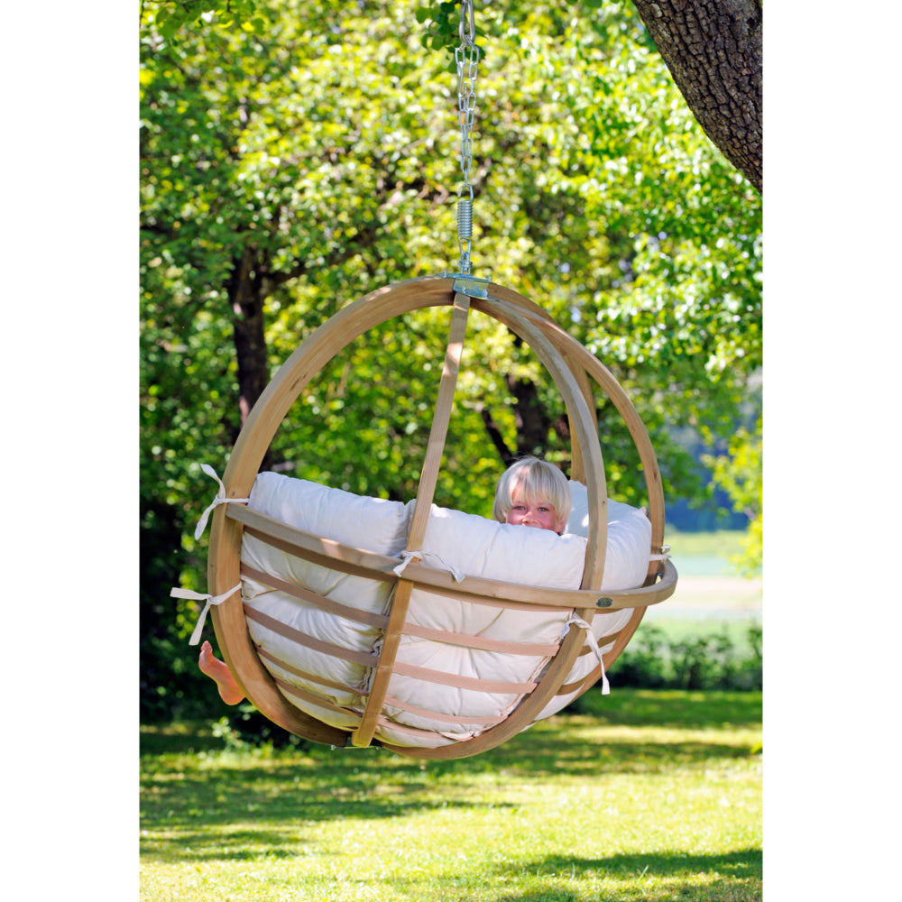 Child sitting in wooden framed hanging egg chair